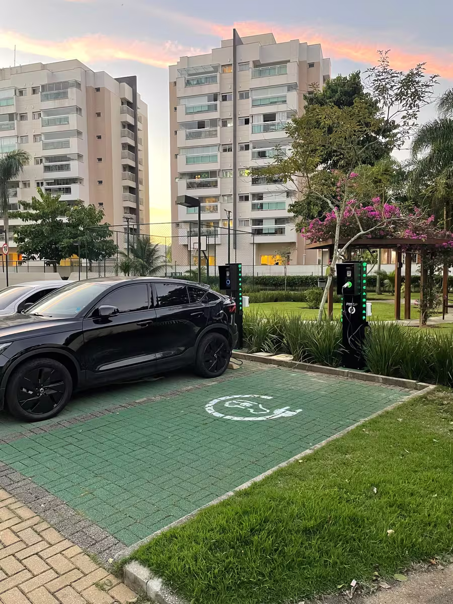 Vaga de recarga PowerUp demarcada em verde, com carro elétrico estacionado em condomínio